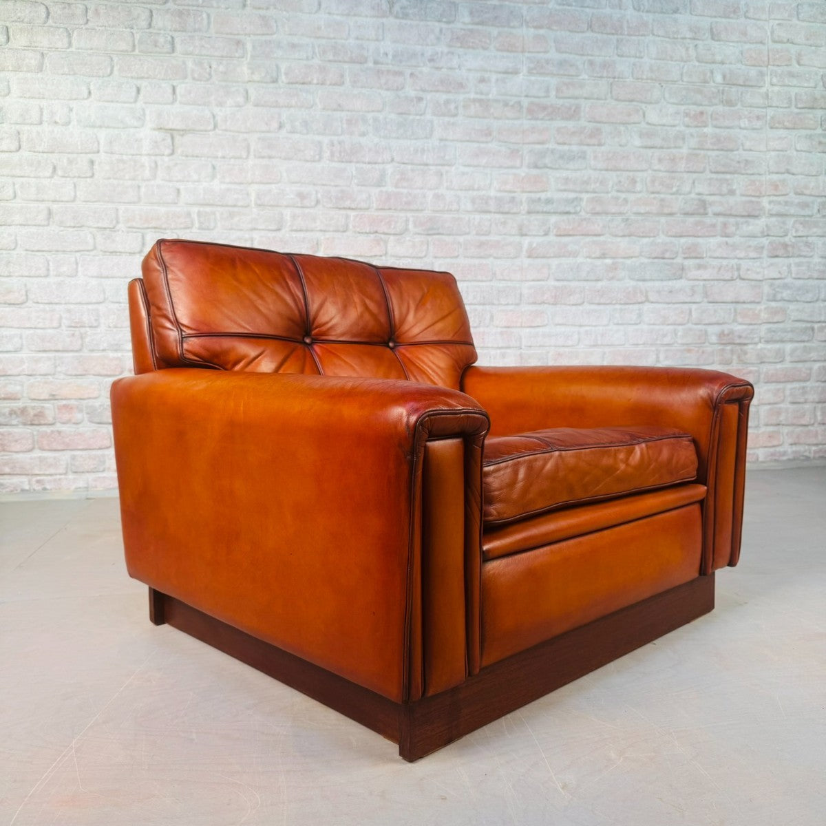 Brown leather sofa against a light brick wall.