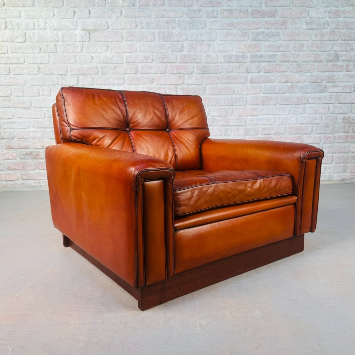 Brown leather sofa against a light brick wall.